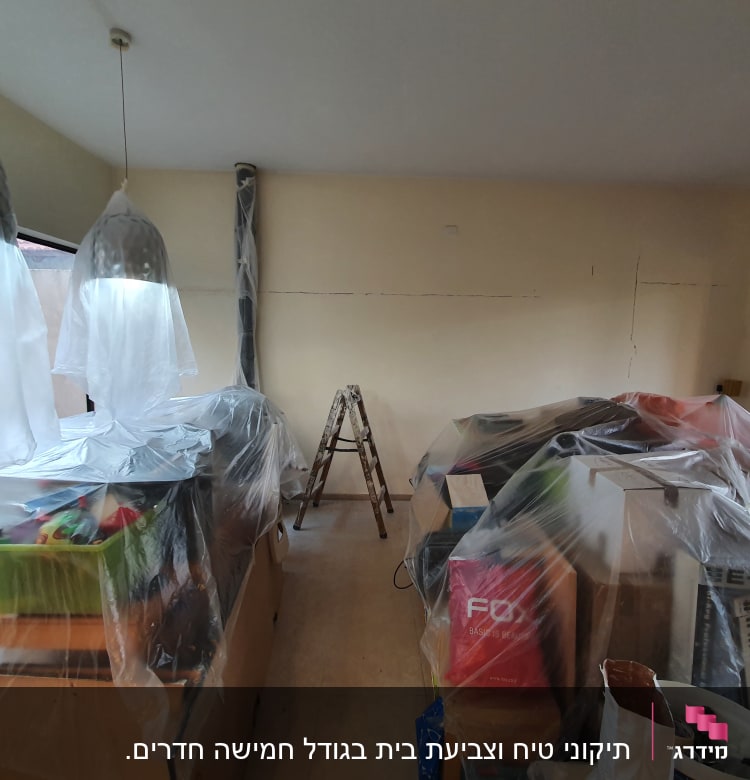 חדר עם רהיטים מכוסים בניילון לקראת צביעה